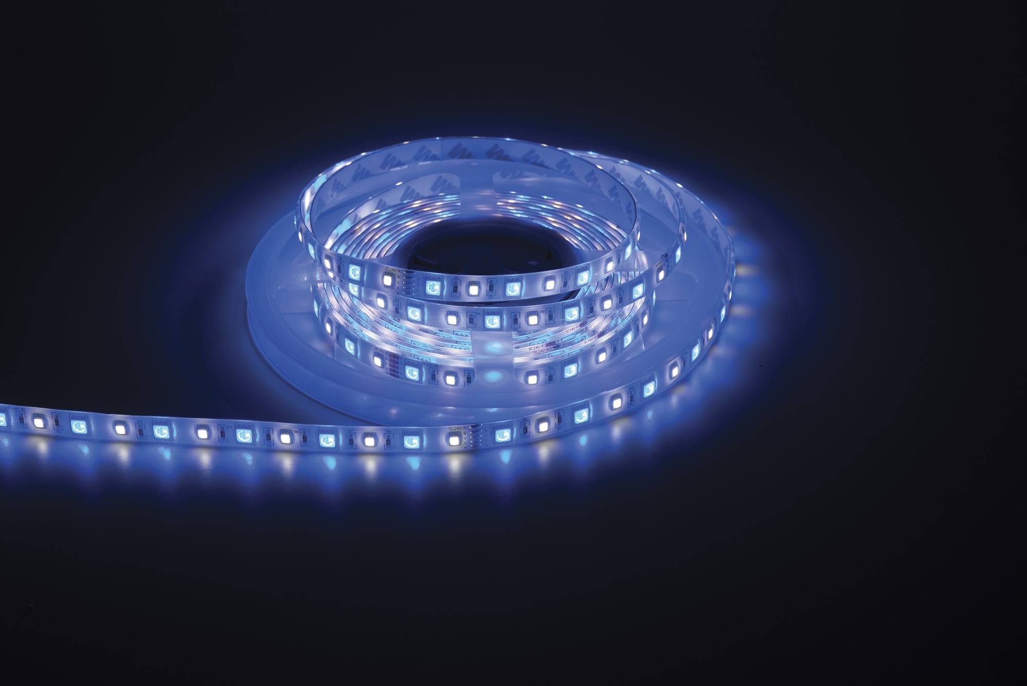 Ein aufgewickelter LED-Streifenleuchte, die in Blautönen leuchtet, vor einem dunklen Hintergrund positioniert und ihr flexibles und leuchtendes Design zur Schau stellend.