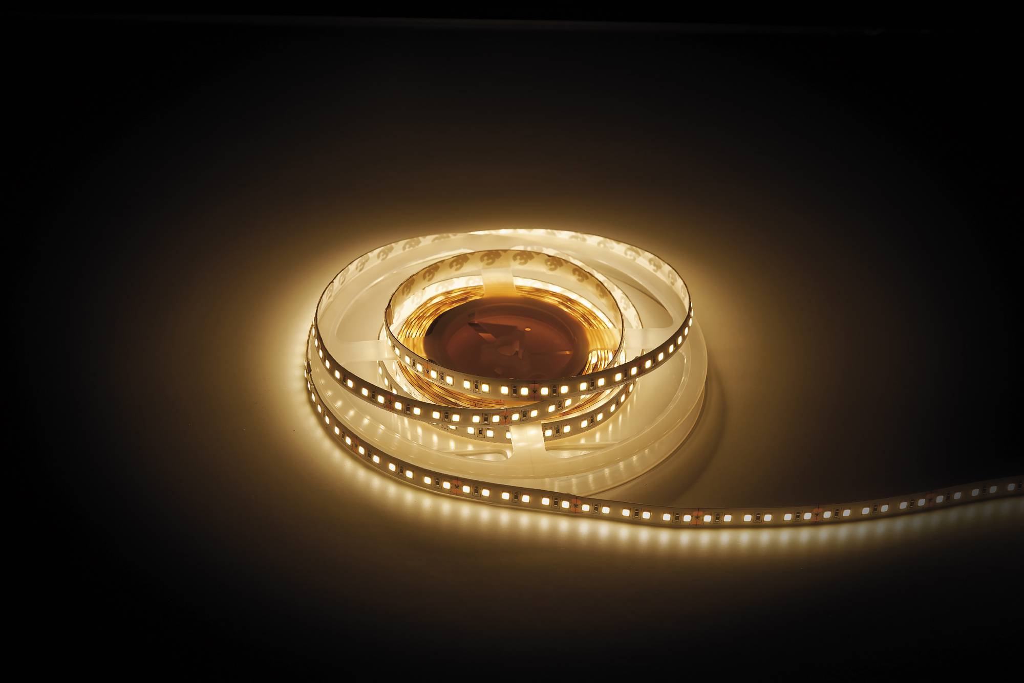 Ein aufgerolltes LED-Streifenlicht gibt ein warmes, gelbliches Licht ab und beleuchtet seine Umgebung mit einem sanften Glanz.