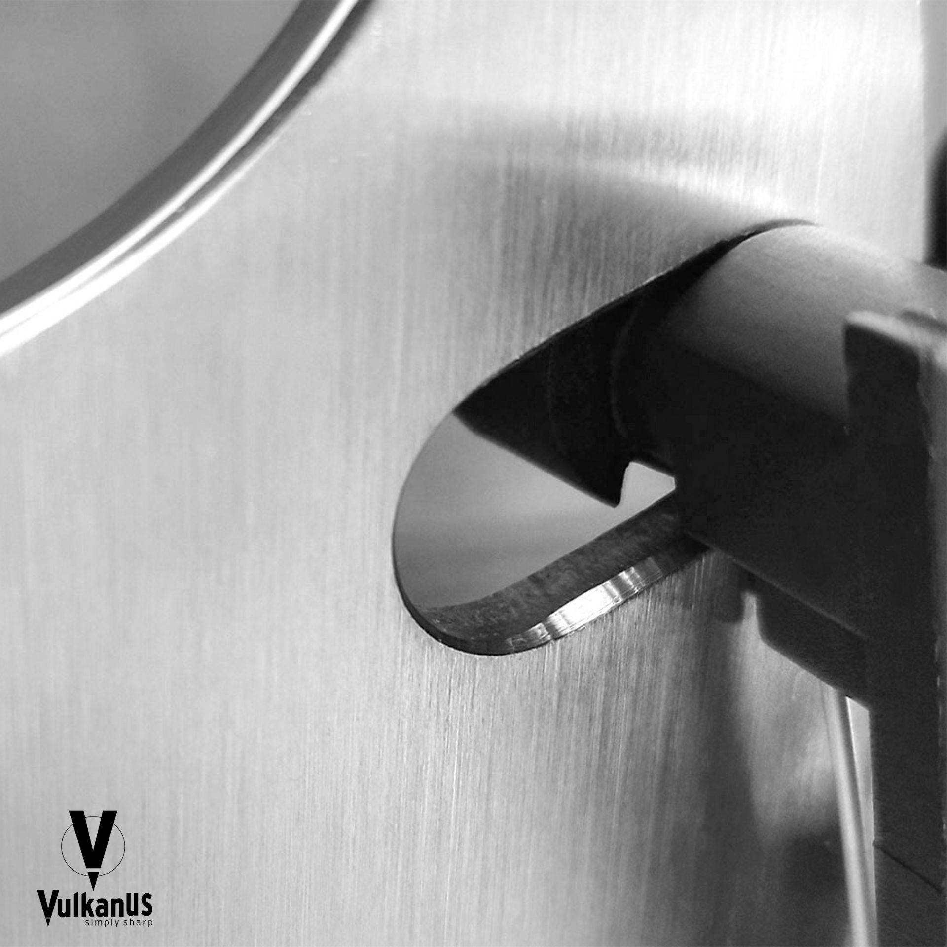 Eine Nahaufnahme eines Messers, das in einem metallischen manuellen Schärfer geschärft wird, wobei seine glatte Klingenkante sichtbar ist.