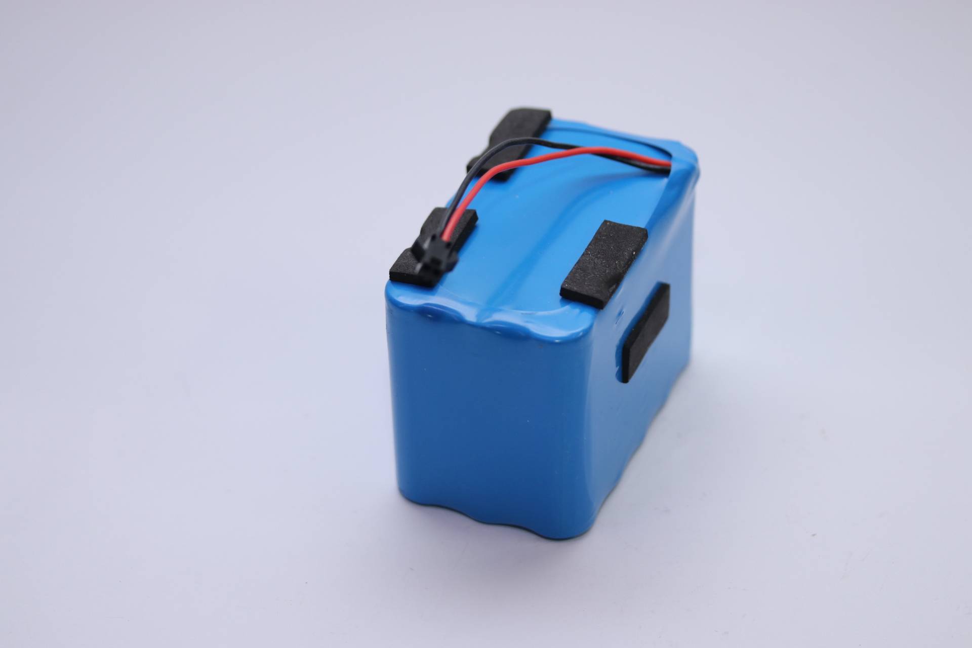 Ein blauer Lithium-Ionen-Akku mit schwarzen Anschlüssen und Drähten, die von oben herausführen, wird zum Betrieb elektronischer Geräte verwendet.