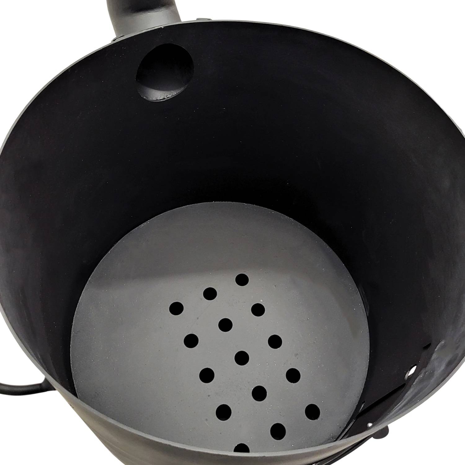 Draufsicht auf einen leeren schwarzen Metallgrillschornstein-Anzünder mit einer perforierten Platte im Inneren, der zum Anzünden von Holzkohle verwendet wird.