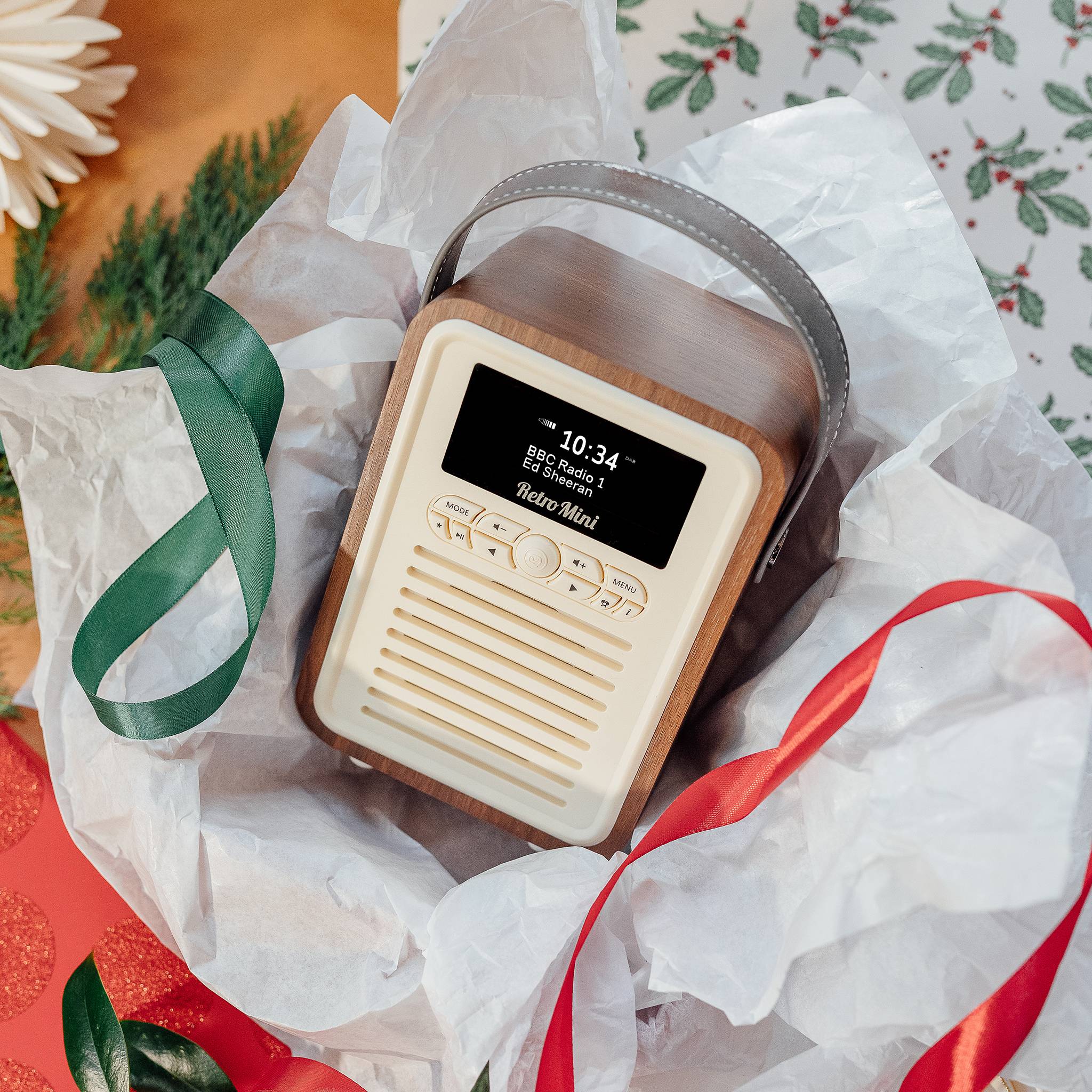Ein Retro-Radio in weihnachtlichem Geschenkpapier und Schleifen, das die Nachricht „10:34 Hello Mini!