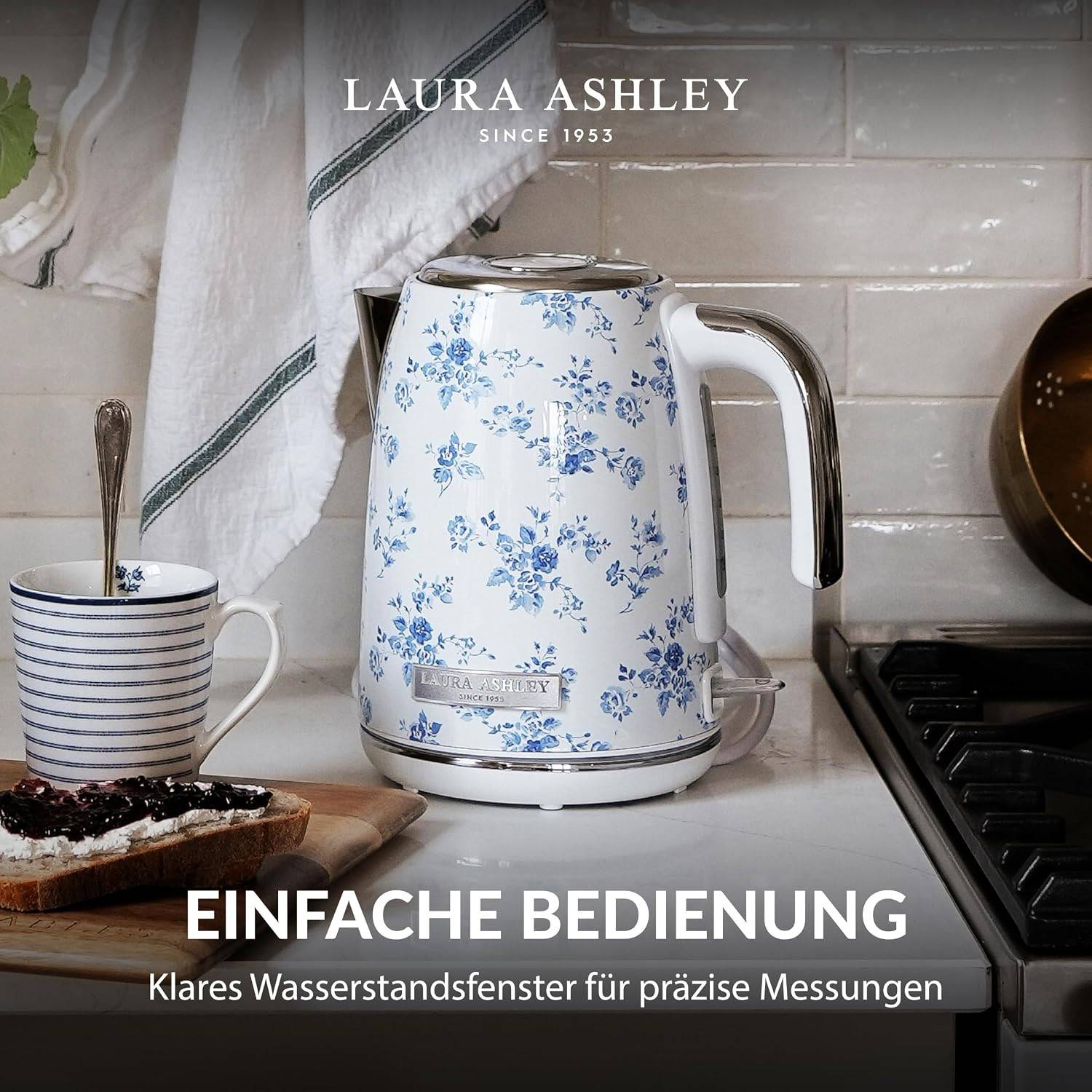 Laura Ashley Blumenmuster Elektrischer Wasserkocher auf einer Küchentheke neben einer gestreiften Tasse und Toast, mit deutschem Text "EINFACHE BEDIENUNG"" und ""Klares Wasserstandsfenster für präzise Messungen"".