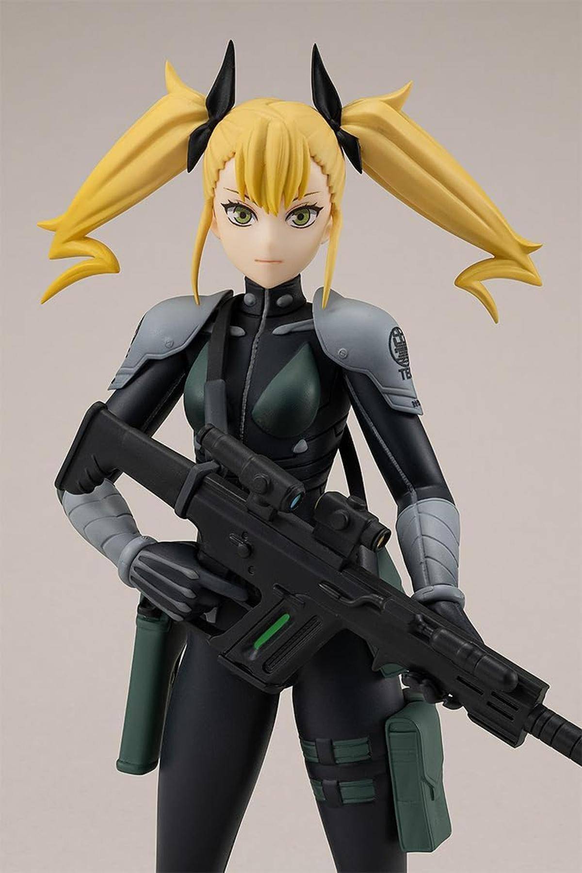 Eine weibliche Anime-Actionfigur mit blondem Zwillingszöpfen, bekleidet mit einem dunklen futuristischen Militäranzug, hält ein großes schwarzes Gewehr.
