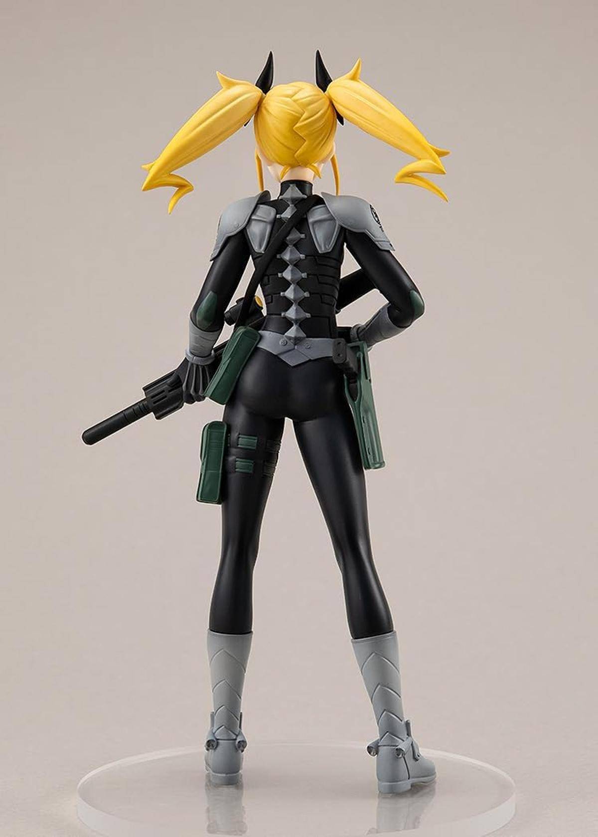 Eine Figur mit blonden Zwillingszöpfen in einem grau-schwarzen Anzug stellt sich mit dem Rücken weg, hält eine Waffe und vermittelt ein Gefühl von Bereitschaft.