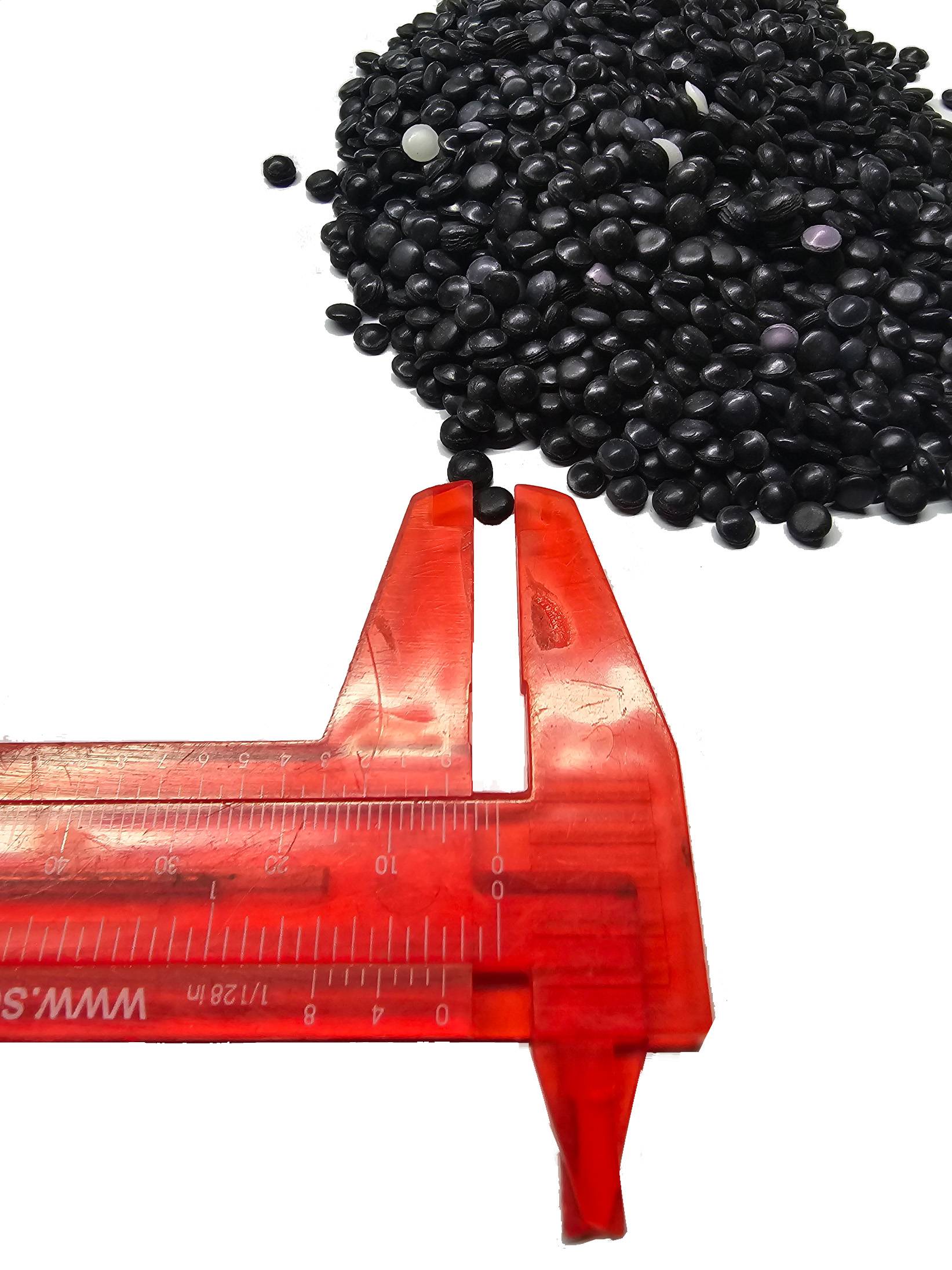 Eine rote Schieblehre misst eine Gruppe schwarzer Kunststoffpellets und zeigt deren Größe für Herstellungs- oder Qualitätskontrollzwecke.