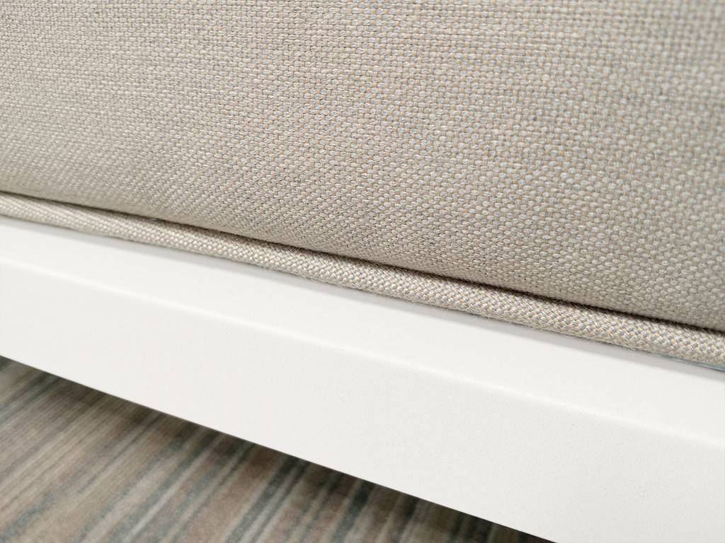 Nahaufnahme einer beigen gepolsterten Sofabasis mit weißem Holzrahmen und Holzboden darunter.