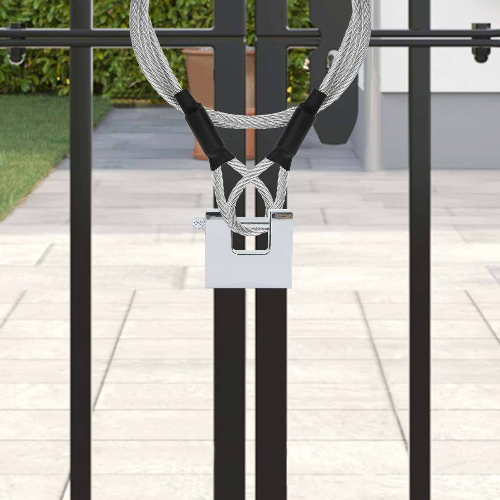 Ein robustes silbernes Vorhängeschloss sichert ein schwarzes Tor mit einem dicken Kabel, das Sicherheit vermittelt. Im Hintergrund ist eine Topfpflanze sichtbar.