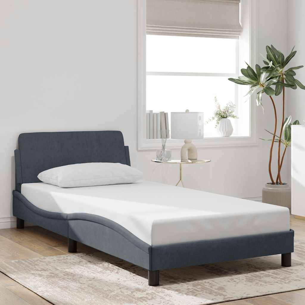 Ein modernes Schlafzimmer mit einem dunkelblau gepolsterten Bett, weißer Bettwäsche, einem Nachttisch mit einer Lampe und Dekoration sowie einem großen Fenster mit einer Pflanze in der Nähe.