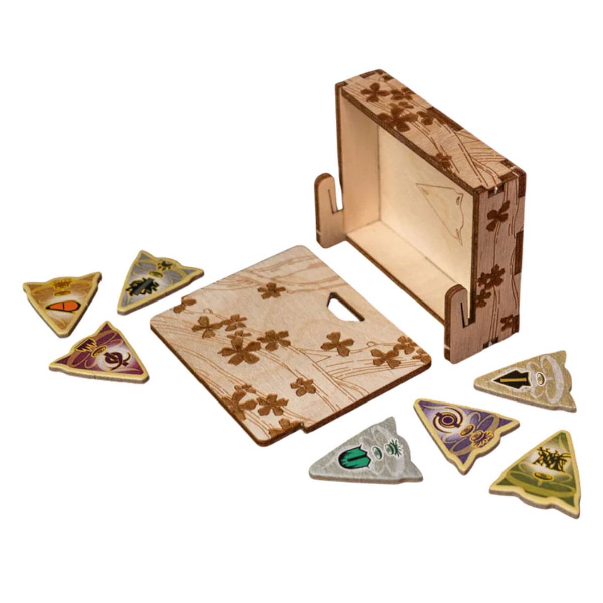 Schachtel mit Blumenmotiven, offen mit einem Deckel und sieben dreieckigen Spielsteinen, von denen jeder einzigartige Symbole und Farben hat, angeordnet darum herum.