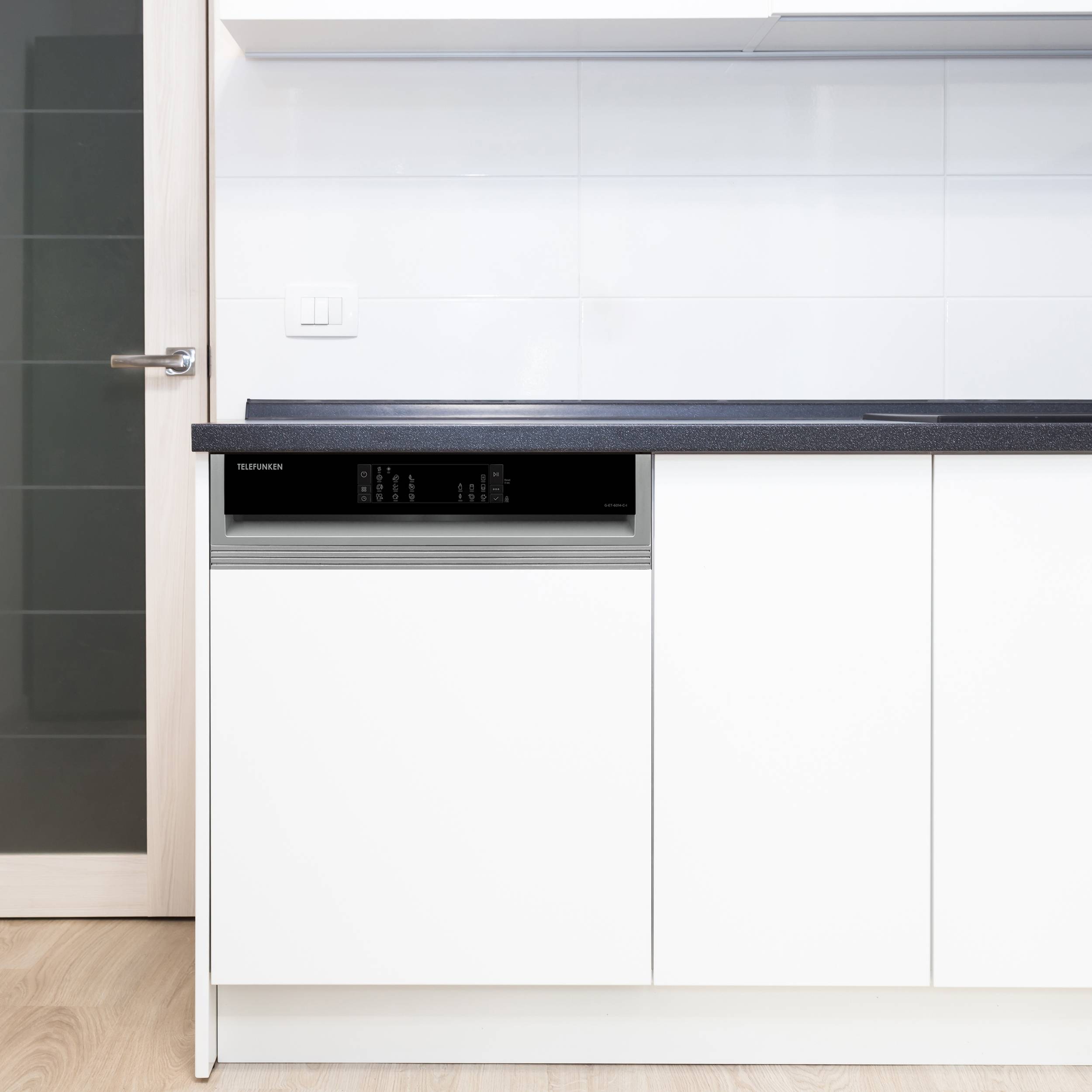 Eine minimalistische Küche mit einer weiß integrierten Spülmaschine in weißen Schränken, einer schwarzen Arbeitsplatte und einem Holzboden.
