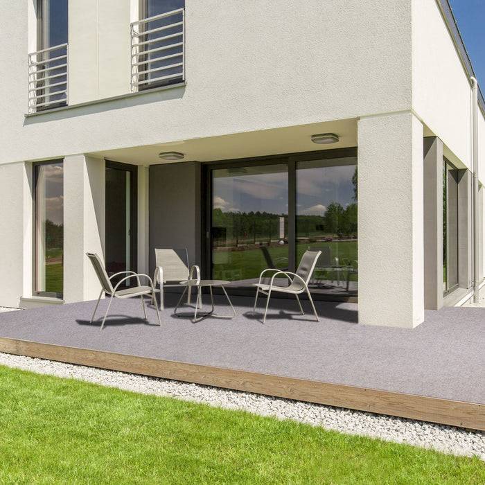 Ein modernes zweistöckiges Haus mit großen Fenstern, eine Terrasse mit Außenstühlen und einem Tisch sowie einen gepflegten Rasen im Vordergrund.