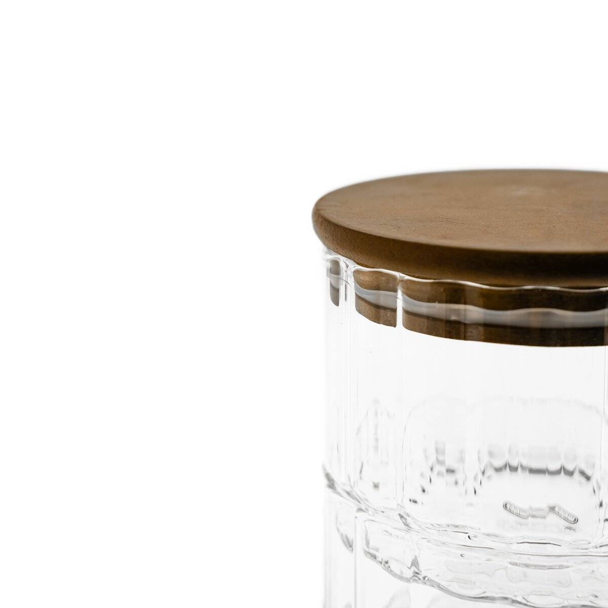 Ein klares Glaskrug mit einem runden Holzdeckel, das charakteristische Verzierungen an seinem Körper aufweist.