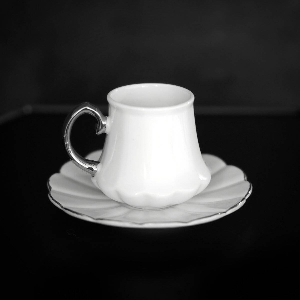 Ein blauer Karton mit sechs beigen Tassen und einer passenden Untertasse, die ordentlich darin angeordnet sind.