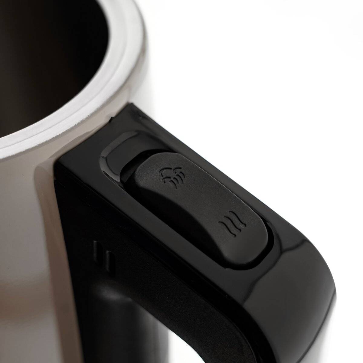 Eine Nahaufnahme eines schwarzen Tassengriffs mit einem Knopf, auf dem ein Dampfsymbol abgebildet ist, was auf eine Heizfunktion hindeutet. Der Metallrand der Tasse ist sichtbar.