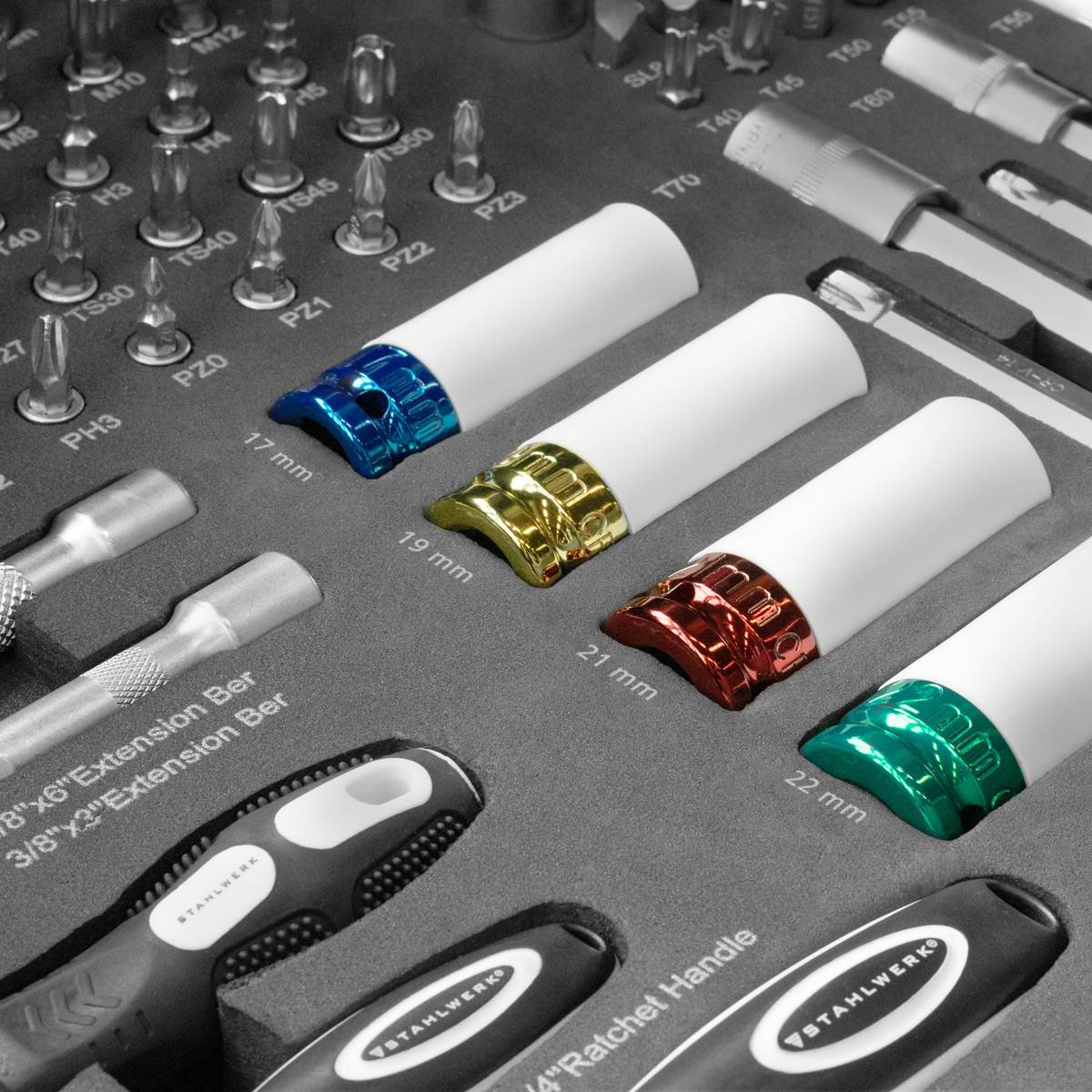 Ein Satz aus Metallstecknüssen in verschiedenen Größen, hervorgehoben durch reflektierende farbige Ringe, ist übersichtlich in einer Werkzeugkasten-Ausstellung angeordnet.