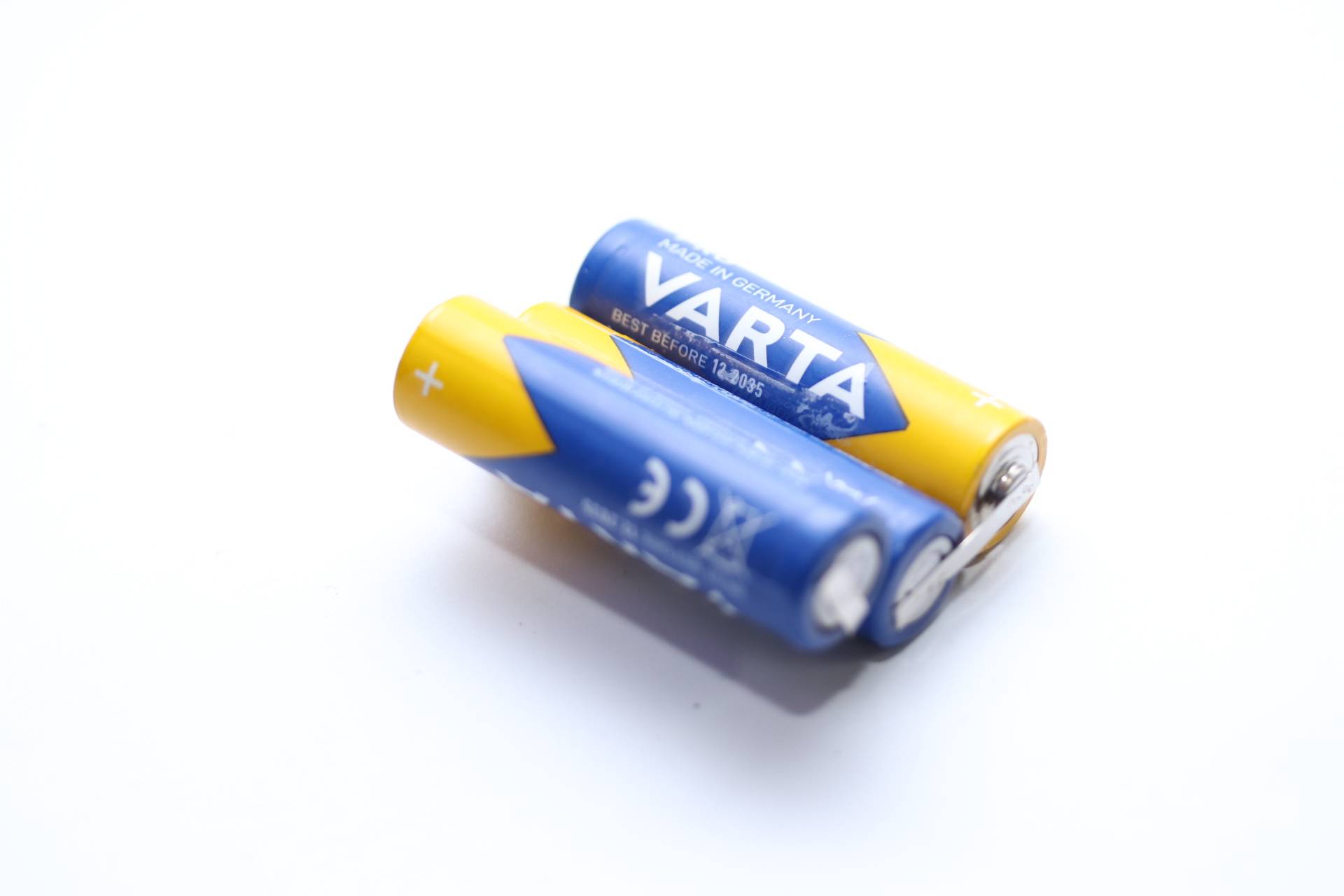 Zwei blaue und gelbe Varta-AA-Batterien mit sichtbaren Plus- und Minuspolen.