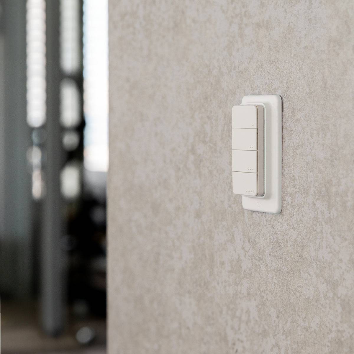 Ein weißer Lichtschalter an einer beigefarbenen Wand in einem sanft beleuchteten Raum.