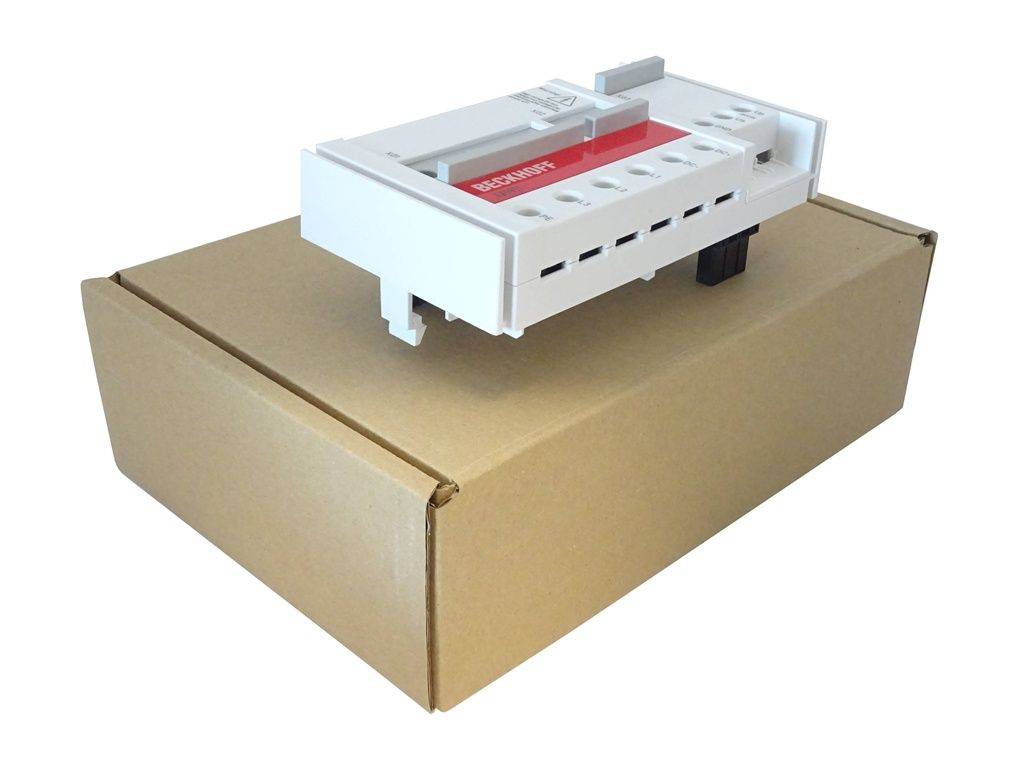 Ein weißes Beckhoff-Industriemodul ruht auf einer geschlossenen Kartonage und zeigt mehrere Anschlüsse und Stecker, die in Automatisierungssystemen verwendet werden.