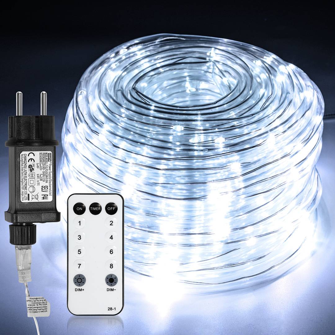 Eine Spule mit LED-Lichterketten gibt helles weißes Licht ab. Daneben befinden sich ein Netzteil und eine Fernbedienung auf einer dunklen Oberfläche.