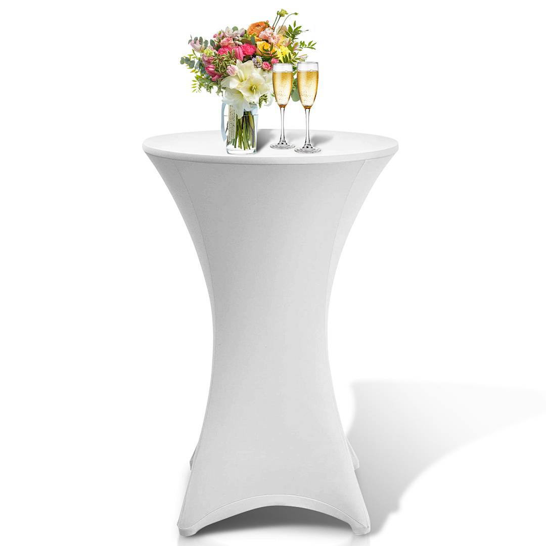 Ein hoher weißer Tisch mit einem Blumenstrauß aus bunten Blumen und zwei Champagnergläsern auf der Oberfläche.