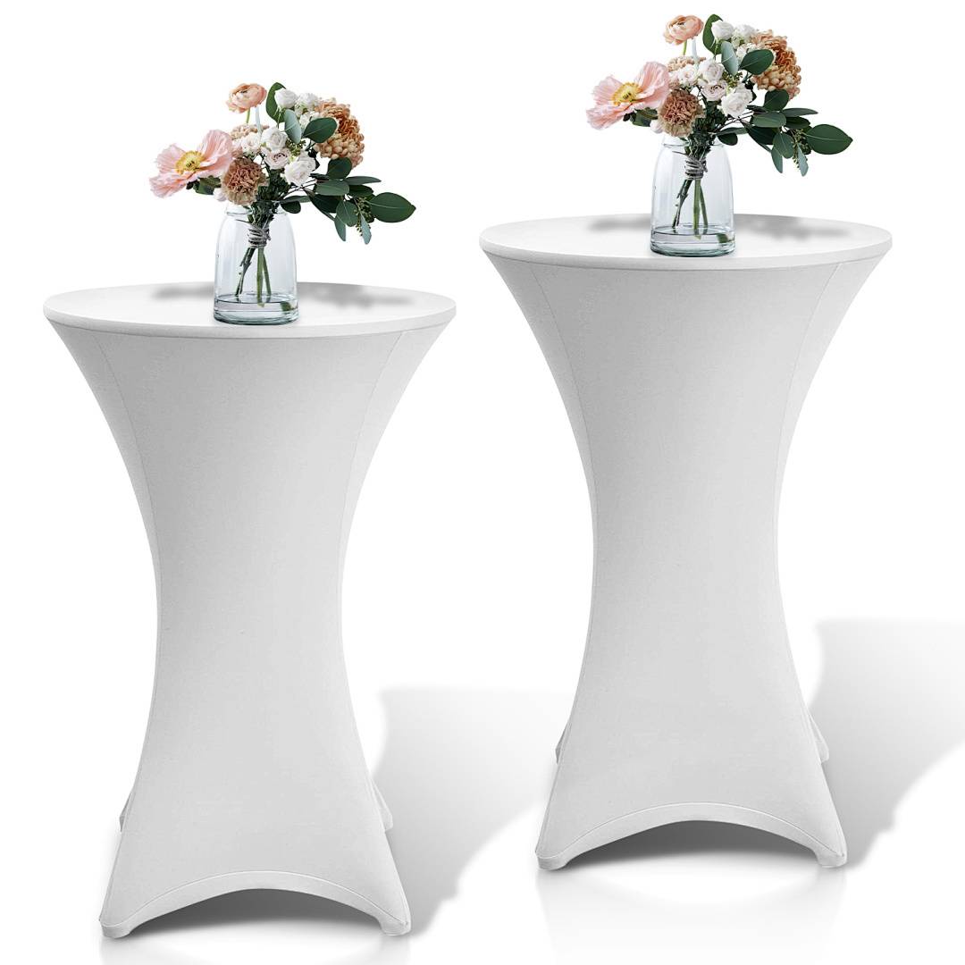 Zwei hohe, runde Tische, die mit weißem Stoff bedeckt sind, jeweils mit einer Glasvase auf der Oberseite gefüllt mit rosa und weißen Blumen, in einer hellen Umgebung platziert.