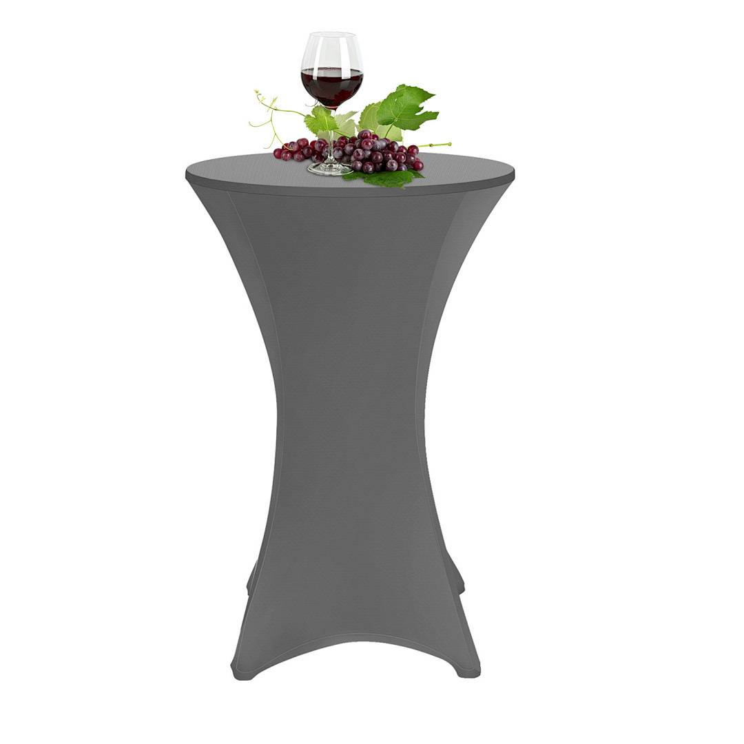 Ein hoher, runder Cocktailtisch mit einer dunklen Abdeckung hält ein Weinglas gefüllt mit Rotwein und steht neben einer Traube und Blättern.