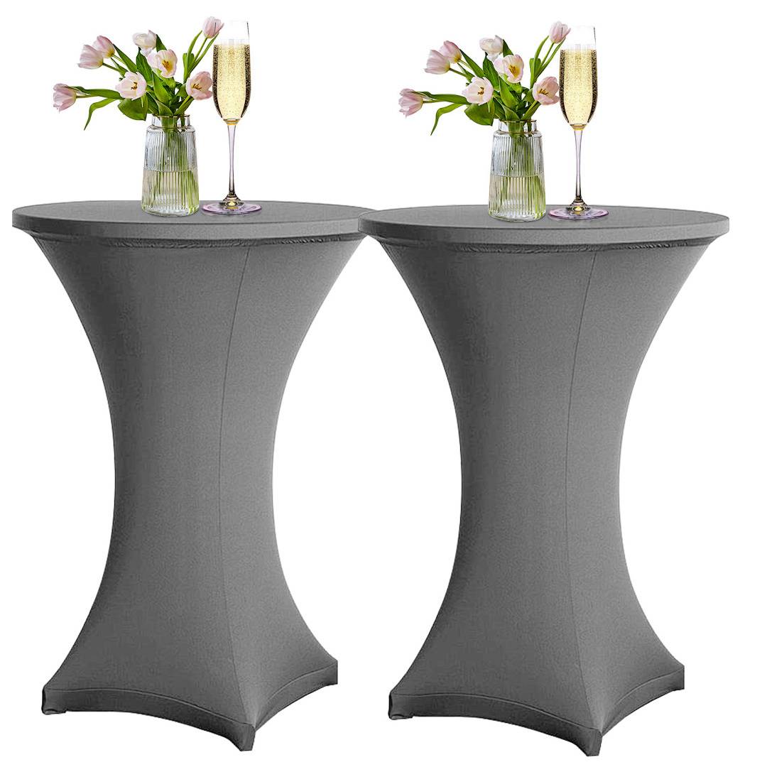 Zwei hohe, runde Tische mit grauen Tüchern, auf denen jeweils eine Vase mit rosa Tulpen und ein Glas Champagner stehen, vor einem neutralen Hintergrund.
