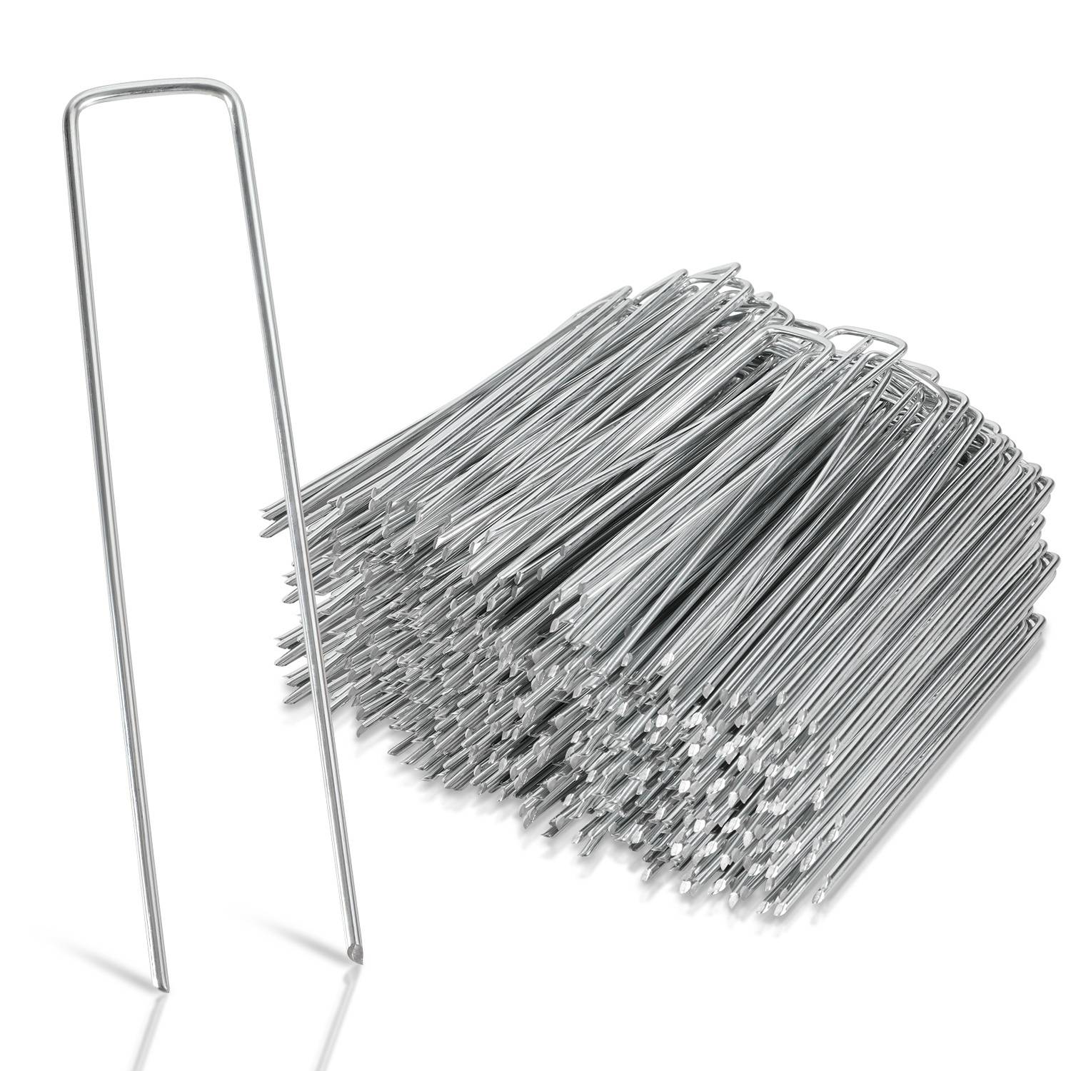 Ein Haufen silberner Metalllandschaftsheftern mit einer aufrecht stehenden auf der linken Seite, verwendet zum Befestigen von Stoffen oder Netzen auf dem Boden.