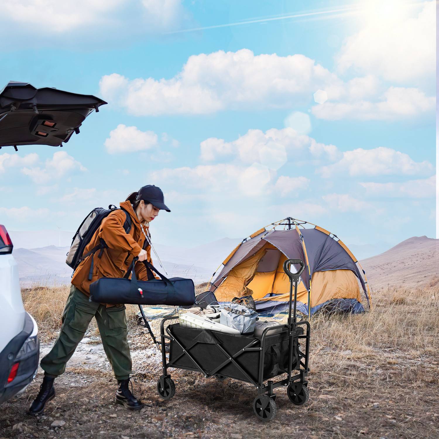 Eine Person in Outdoor-Ausrüstung baut ein Lager neben einem Zelt und einem Auto mit offener Heckklappe unter klarem Himmel auf. Sie ordnet Campingausrüstung auf einem Wagen an.