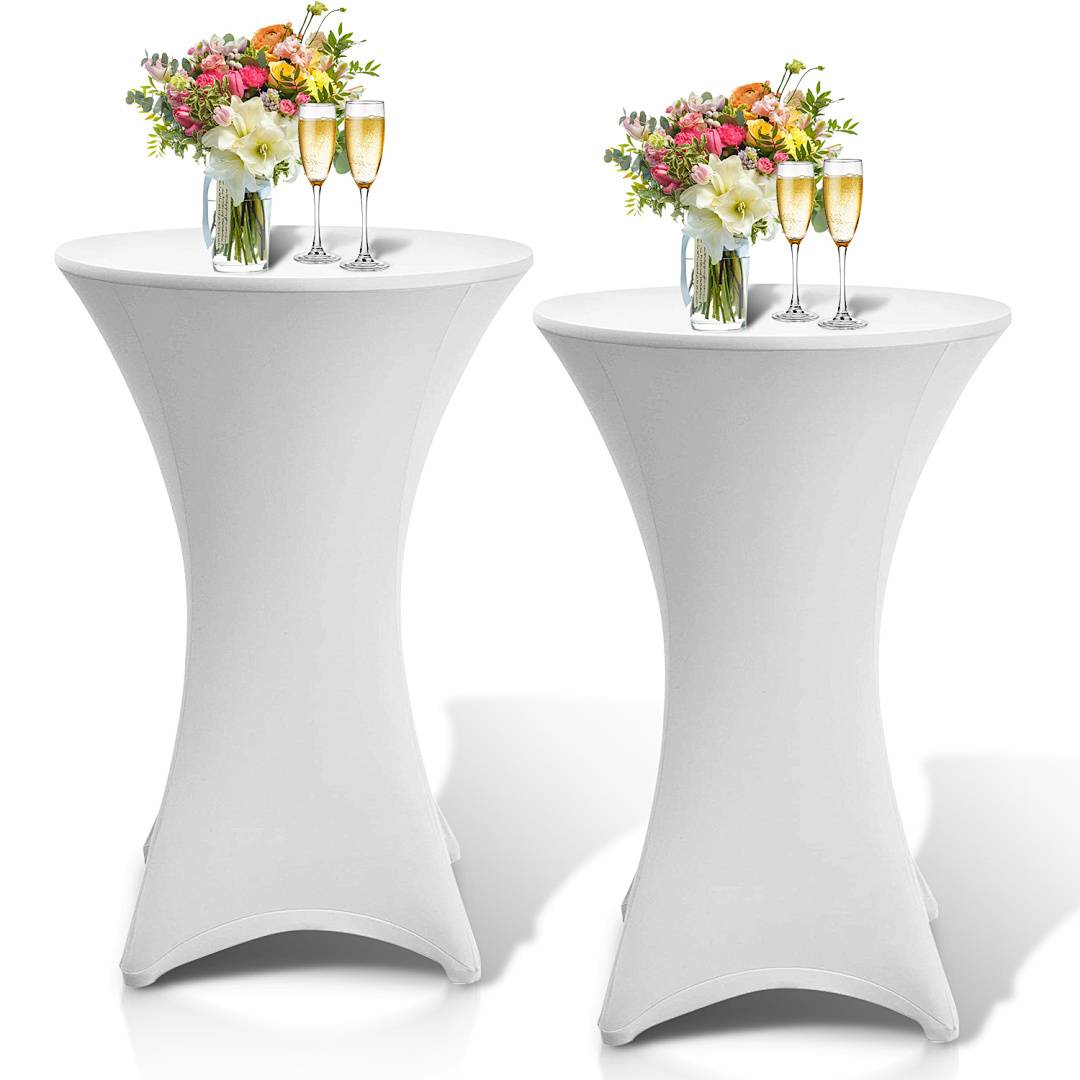 Zwei hohe runde Tische mit weißem Stoff drapiert, jeder mit Blumenarrangements und zwei Champagnergläsern bestückt, was auf ein festliches Ereignis hindeutet.