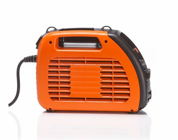 Ein tragbarer orangefarbener Generator mit Griff und belüfteten Seiten, verbunden durch ein schwarzes Stromkabel, auf weißem Hintergrund.