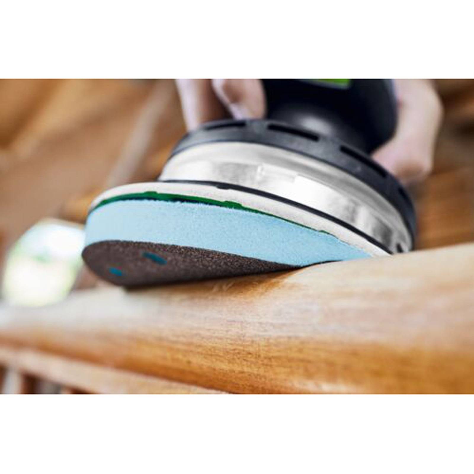 Eine Hand verwendet einen Elektroschlifer zum Glätten der Kante einer Holzoberfläche und zeigt die laufende Holzbearbeitung oder Möbelfinish.