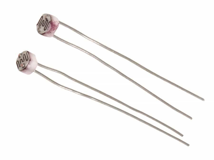 Zwei lichtspeichernde Widerstände (LDRs) mit gewellten leitfähigen Mustern auf ihren Oberflächen, die ihr elektronisches Bauteildesign zeigen.