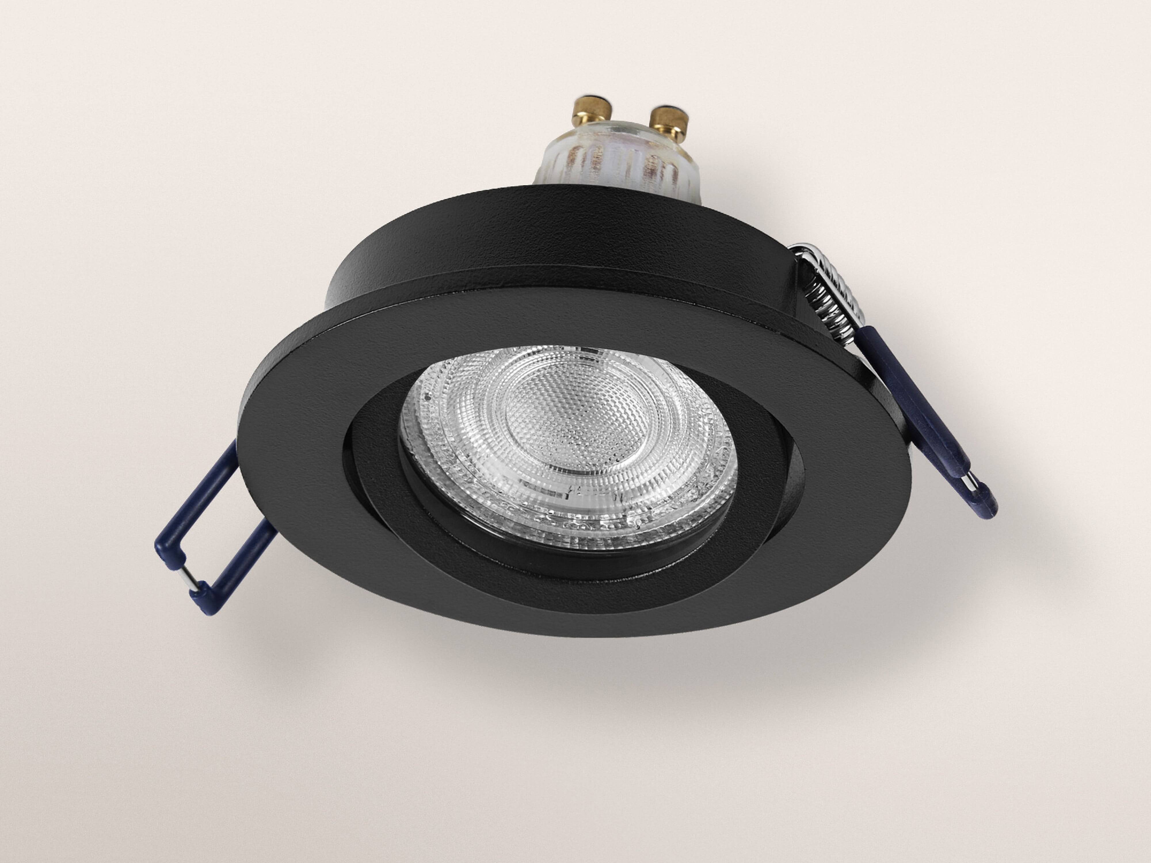 Ein schwarzes, eingelassenes Deckenleuchten-Modul mit zwei Federclips und einer klaren Glühbirne, fotografiert vor einem neutralen Hintergrund.