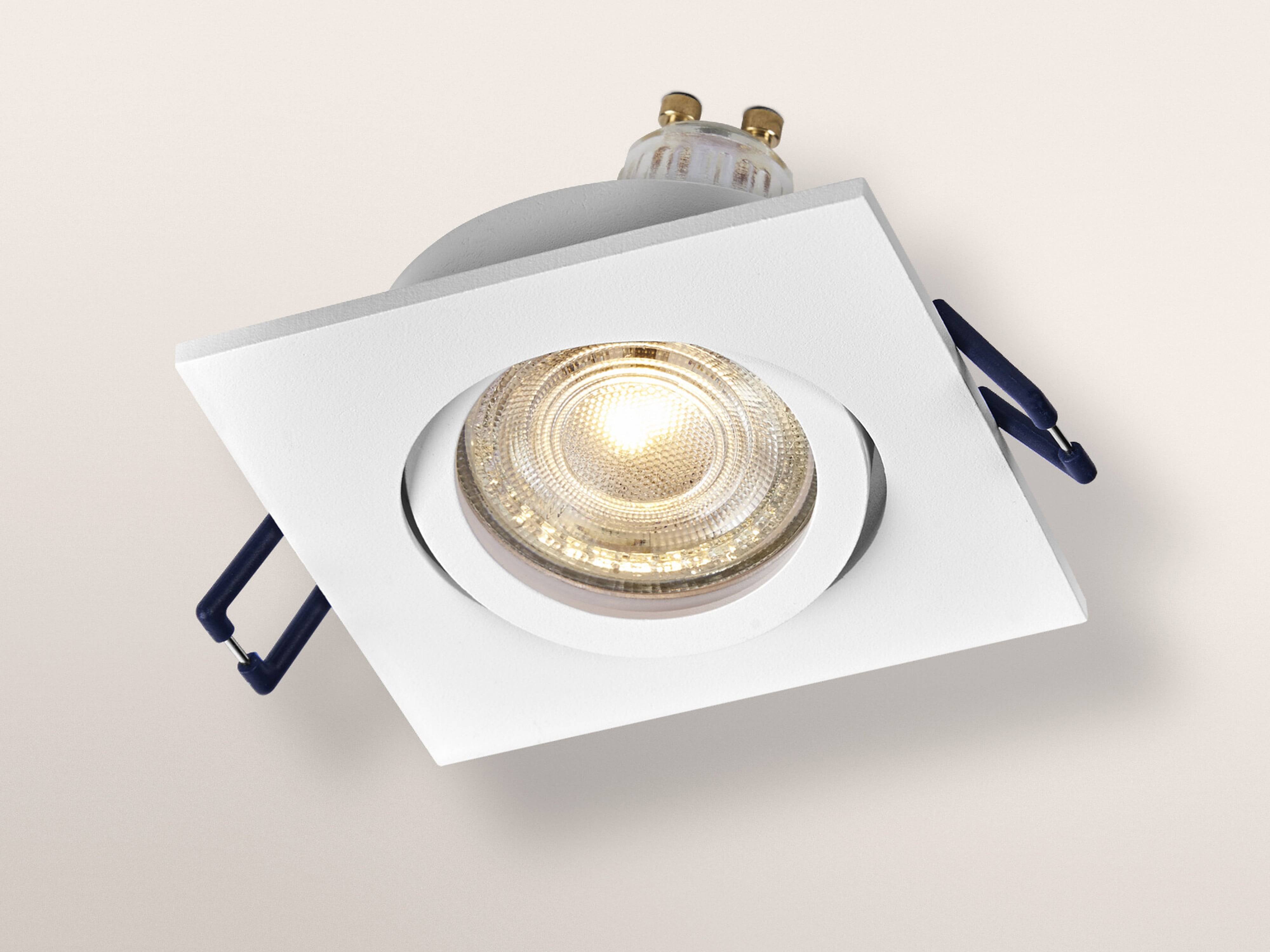 Ein weiß quadratisches, eingelassenes Deckenleuchten mit einer leuchtenden runden Glühbirne, vor einem weichen beigen Hintergrund.