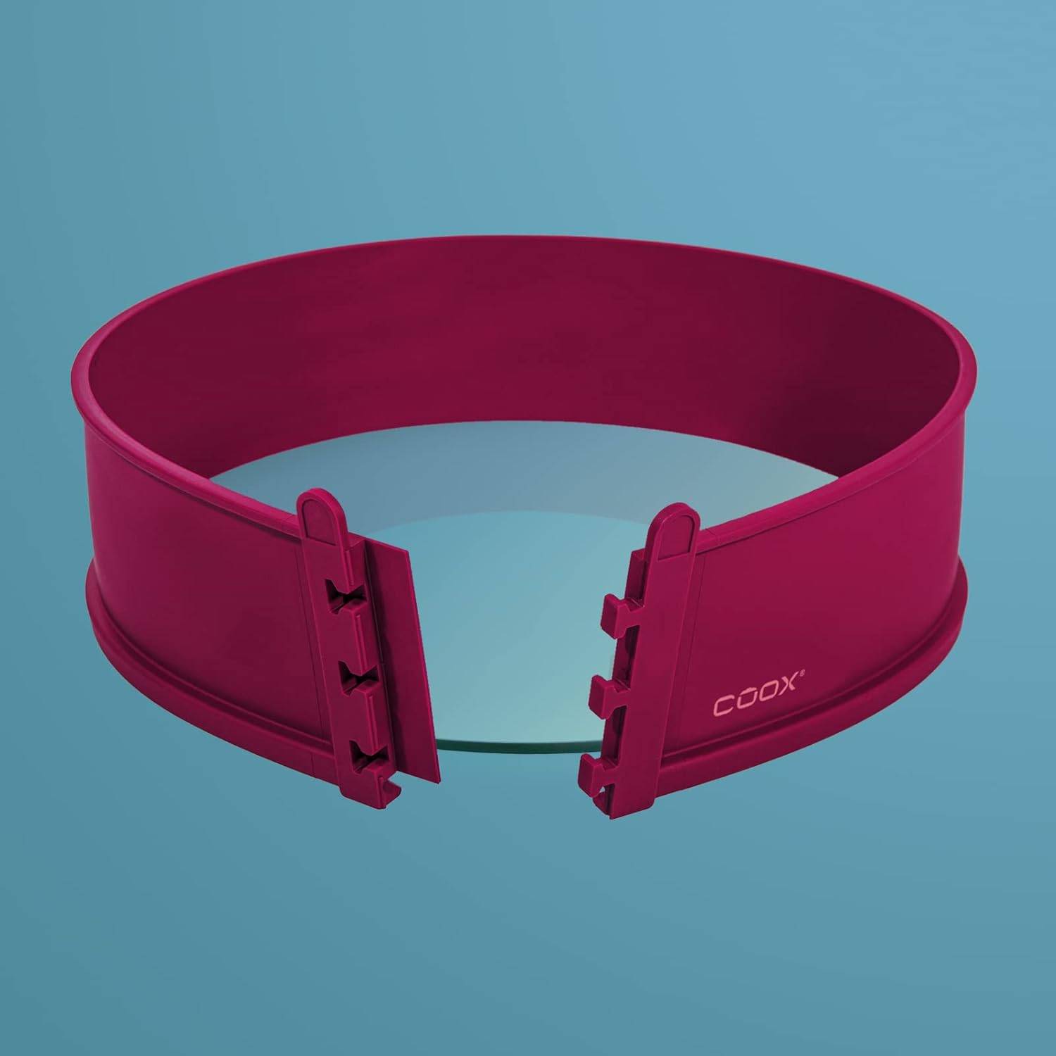 Eine rote, verstellbare Silikon-Kuchenform mit Verschlussmechanismus wird in einer kreisförmigen Form vor blauem Hintergrund gezeigt.