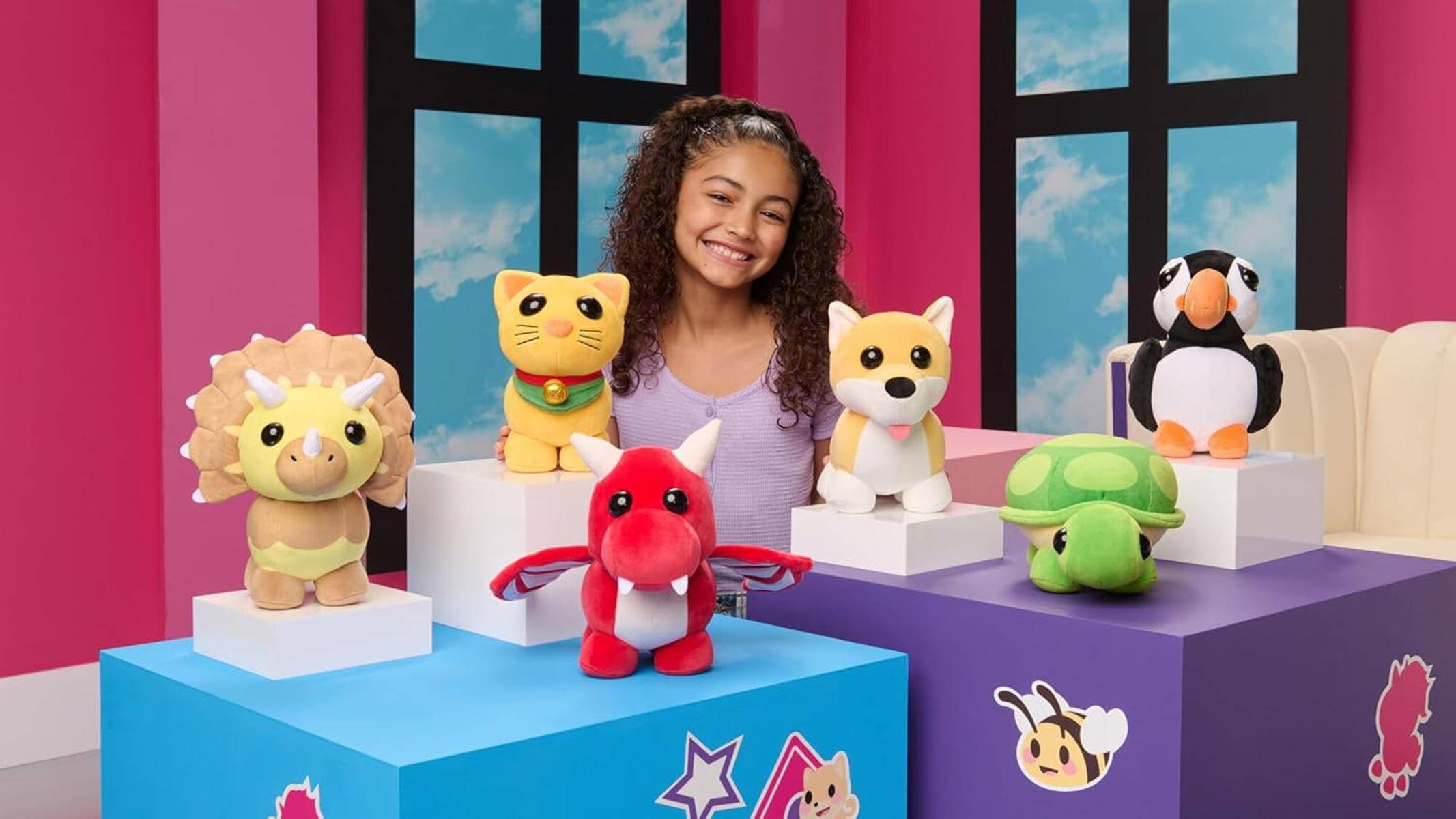 Ein Kind lächelt, umgeben von Plüschtieren, darunter ein roter Drache, eine Katze und ein Hund, vor einem farbenfrohen Hintergrund mit Sterndekorationen.