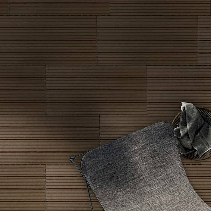 Grauer, gepolsterter Stuhl vor einem Wandhintergrund mit Fliesenmuster, teilweise sichtbar.