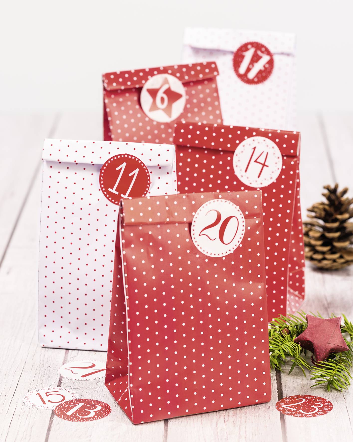 Fünf dekorative Tüten mit den Nummern 6, 11, 14 und 20 sowie anderen Nummern, die ein Countdown- oder Adventsthema suggerieren, mit festlichen Dekorationen.