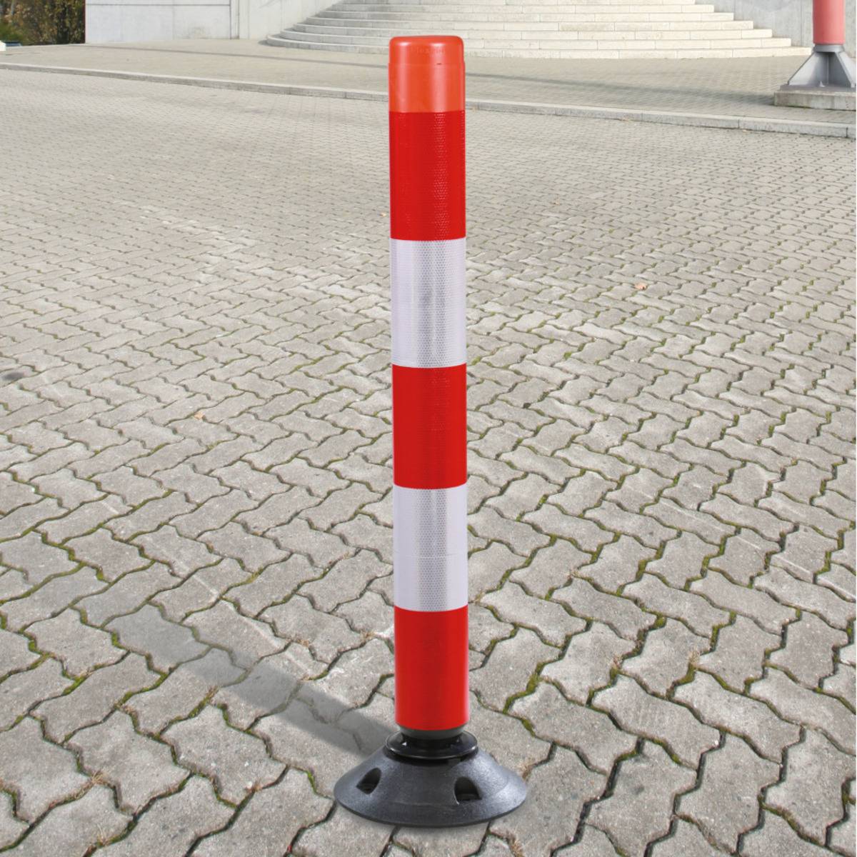Ein rot-weißer gestreifter Verkehrspfosten steht auf einer gepflasterten Oberfläche und kennzeichnet eine Grenze oder einen gesperrten Bereich.