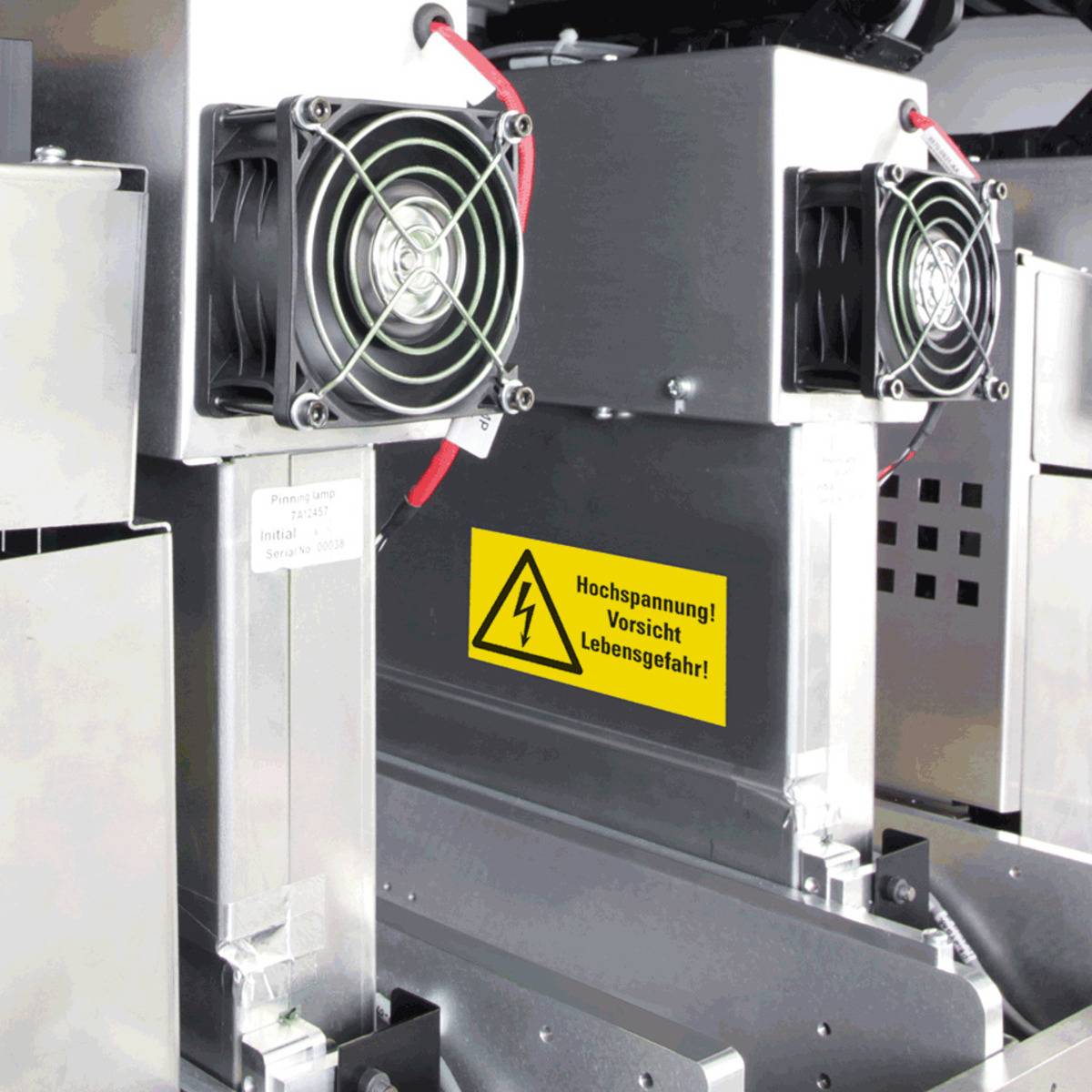 Zwei Industriekühlventilatoren, die auf metallener Ausrüstung montiert sind, in der Nähe eines gelben Warnschildes mit einem Blitzsymbol und deutschem Text.