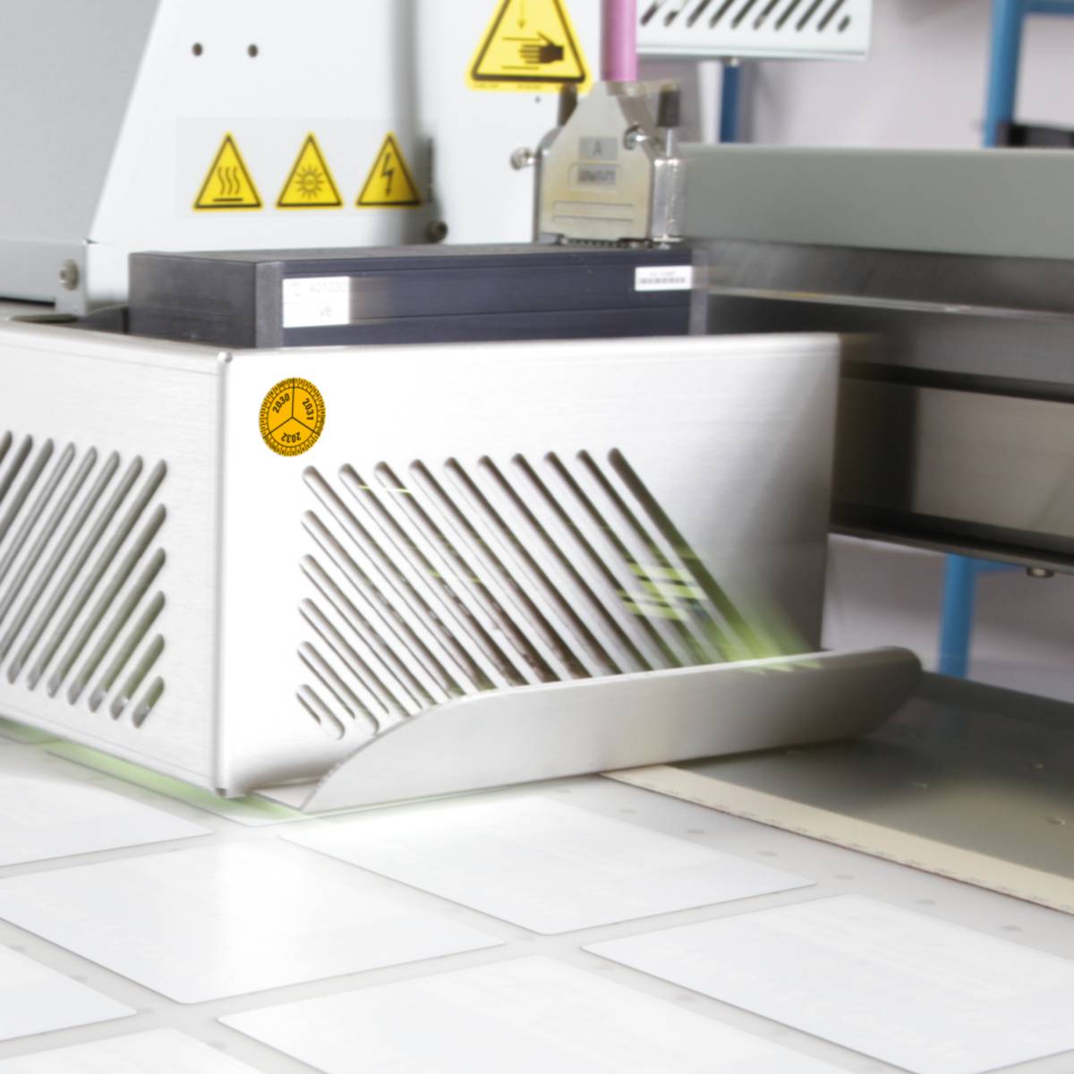 Eine Nahaufnahme von Industrieausrüstung mit Belüftungsgittern und Warnsymbolen, die über eine ebene Fläche läuft.