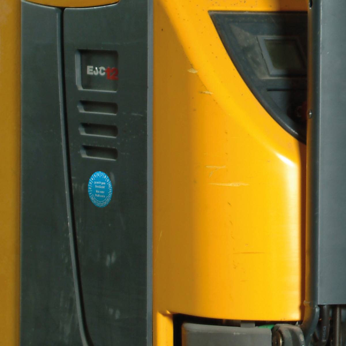 Nahaufnahme von Industriemaschinen mit einem gelb-schwarzen Gabelstapler mit sichtbaren Markenetiketten und Bedienfeld.