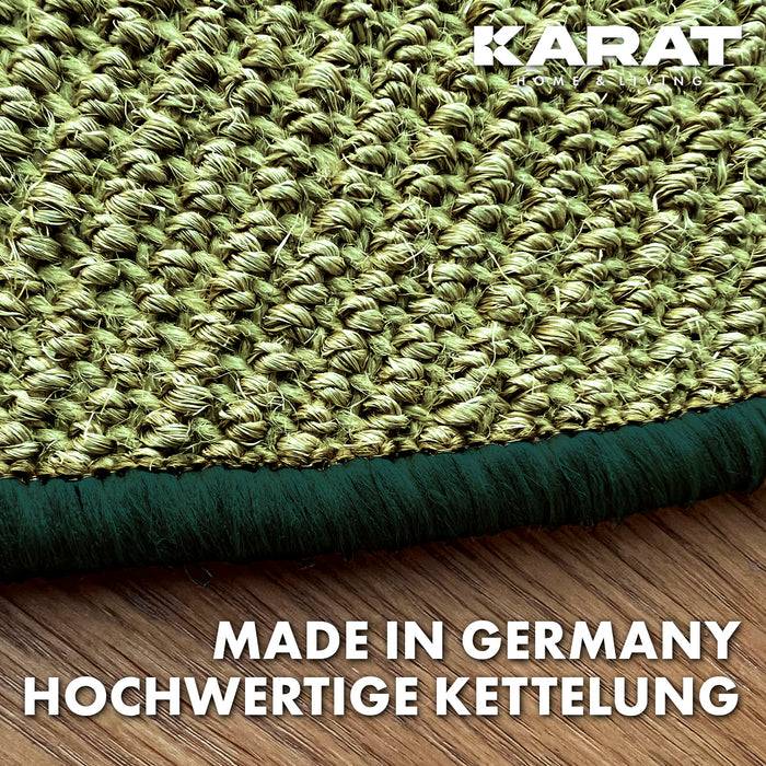 Eine Nahaufnahme eines strukturierten grünen Teppichs mit grünem Rand auf einem Holzboden. Der Text lautet „MADE IN GERMANY HOCHWERTIGE KETTELUNG