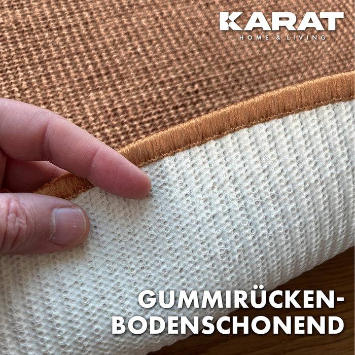 Nahaufnahme einer Hand, die eine Ecke eines strukturierten Teppichs anhebt und zeigt eine Gummirückseite. Der Text lautet „Gummirücken-Bodenschonend