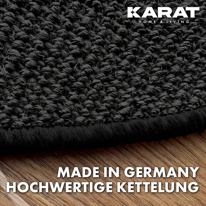 Nahaufnahme einer schwarzen strukturierten Teppichkante auf Holzbodenbelag mit dem Text „Made in Germany Hochwertige Kettelung