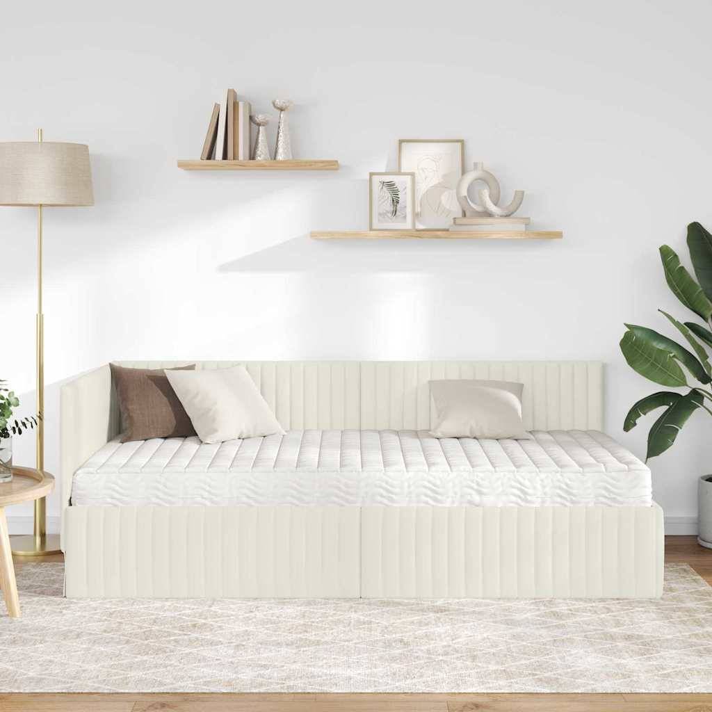 Ein minimalistisches Wohnzimmer mit einem hellbeigefarbenen Tagesbett, Kissen, hölzernen Regalen mit Dekoration, einer Stehlampe und einer grünen Topfpflanze.