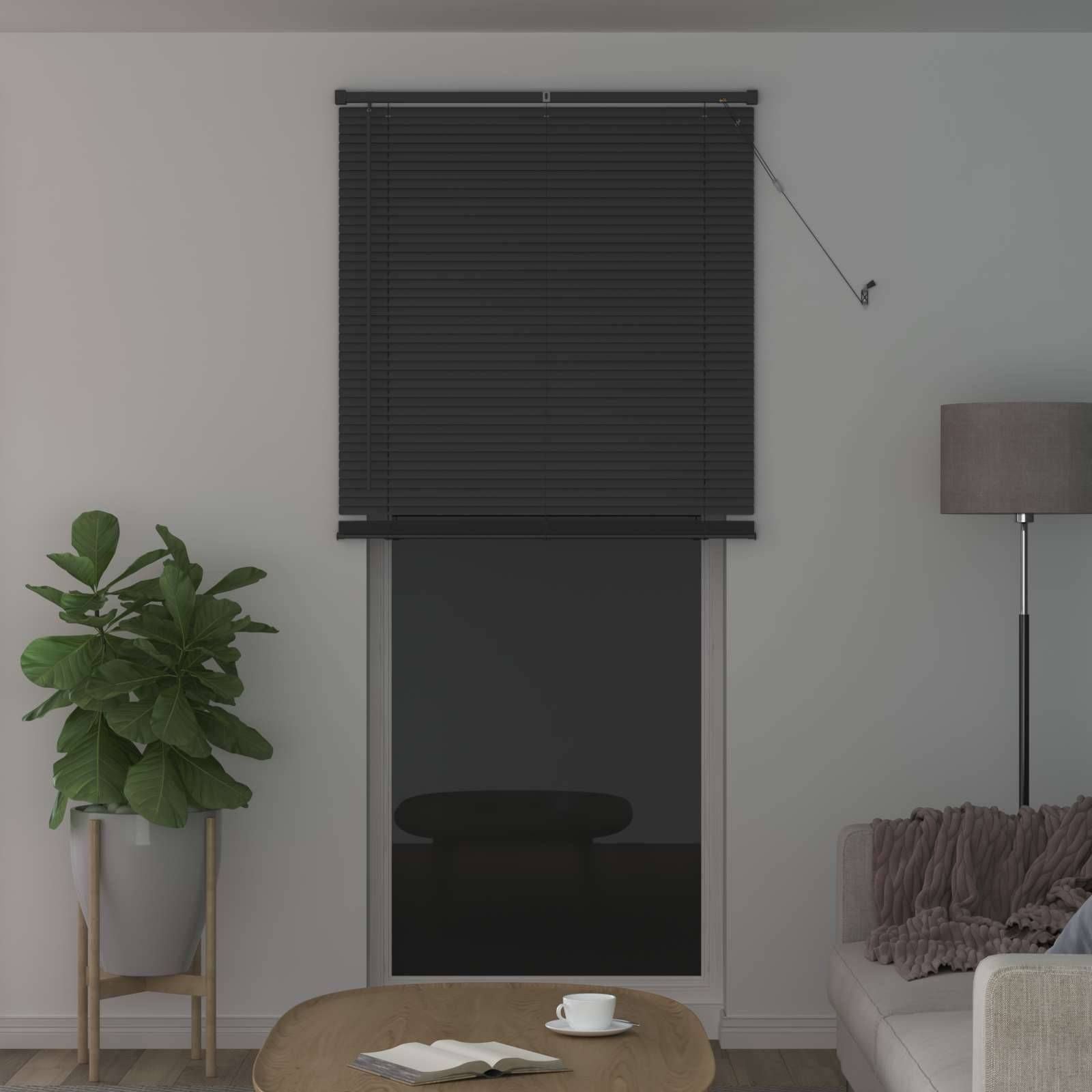 Wohnzimmer mit einem Fenster, das mit dunklen Jalousien verdeckt ist, einer Stehlampe, einer Pflanze auf der linken Seite und einem Couchtisch mit einer Tasse im Vordergrund.