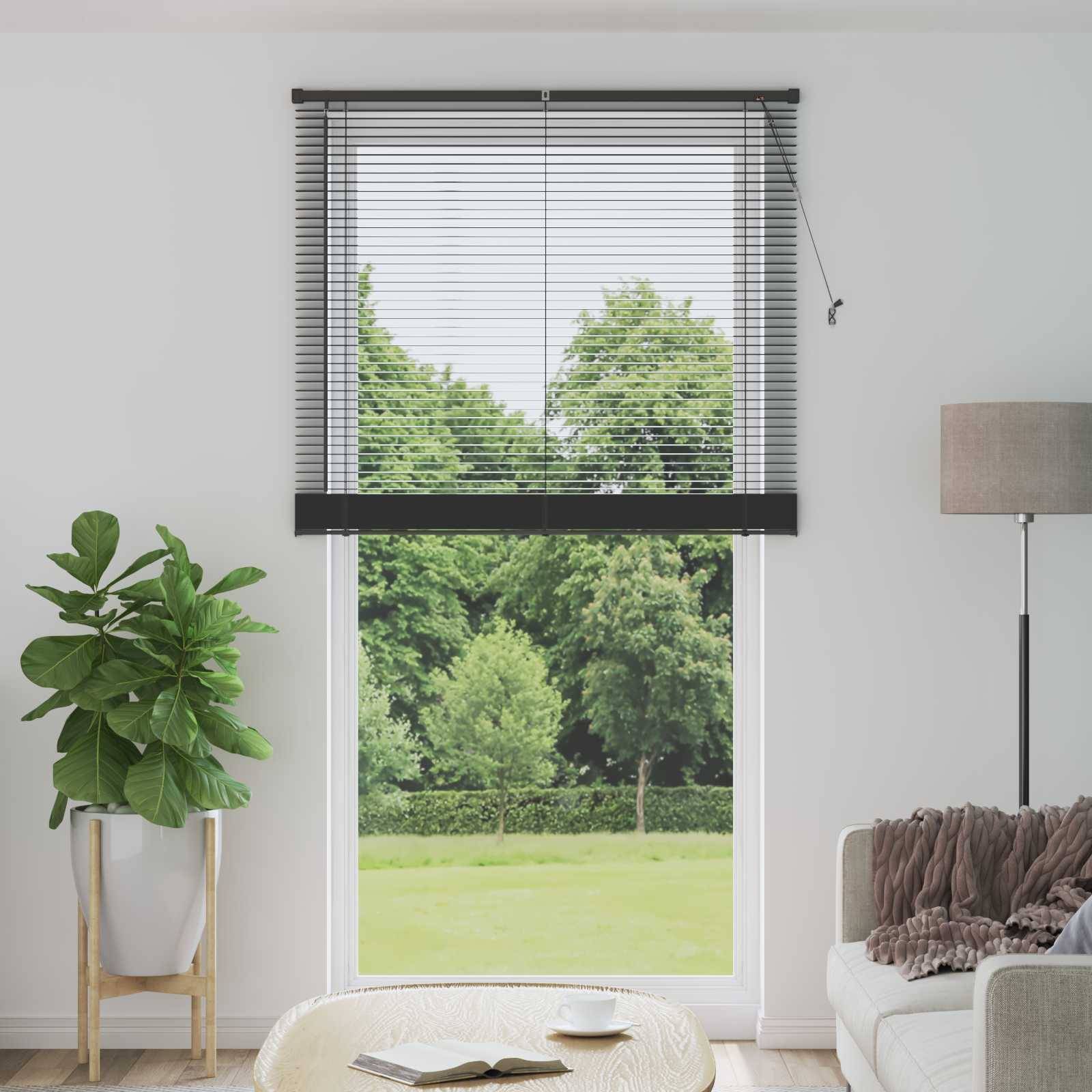 Ein helles Wohnzimmer mit einem großen Fenster bietet einen Blick auf üppig grüne Bäume draußen. Das Interieur umfasst eine Topfpflanze und eine Stehlampe.